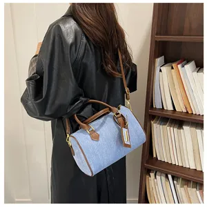 Retro denim Boston handbag detail view, featuring chic brown leather handles and shoulder strap.
