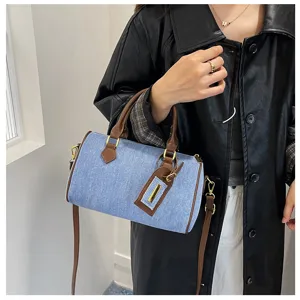 Denim Boston handbag detail showcasing blue fabric, brown leather trim, and stylish handle design.