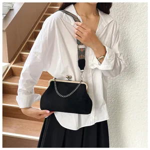 Detailed view of women's vintage black suede cross-body bag with decorative chain strap.
