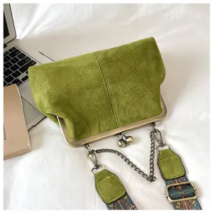 Vintage green suede kiss-lock shoulder bag detail, featuring retro chain and ethnic patterned strap.