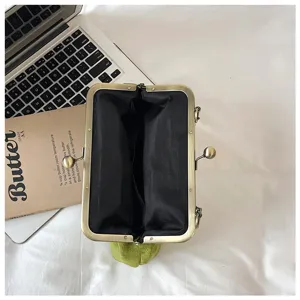 Retro kiss lock clutch bag detail, green velvet purse with metal frame, open interior view.