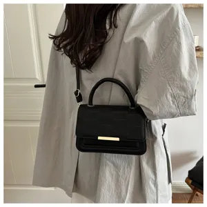 Vue détaillée d'un sac bandoulière noir texturé avec motif à carreaux et fermoir en métal.