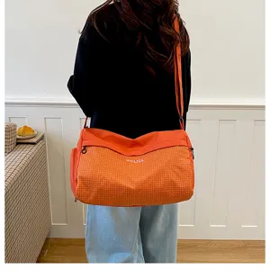 Small travel duffel bag in orange grid design, casual crossbody sports gym bag detail view.