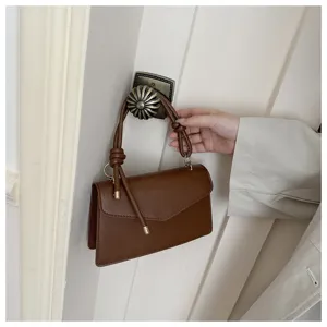 Brown leather handbag detail shot, minimalist style, top handle and crossbody design