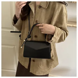 Close-up of a stylish black leather crossbody shoulder bag worn with a chic brown jacket.