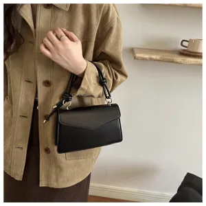 Close-up detail of stylish black leather shoulder bag with chic knotted handle and flap closure.