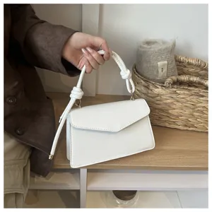 White PU leather small handbag detail shot showing the elegant knotted handle and flap design.