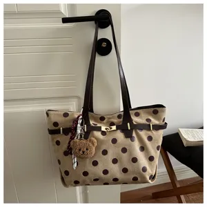 Borsa shopper vintage a pois con manici marroni e grazioso ciondolo orsetto per look.