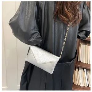 Detailed shot of a silver envelope crossbody bag featuring a chic chain strap and textured finish.