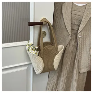 Detailansicht der geflochtenen Handtasche mit braun-weißer Kordelstruktur und Blumendekor.