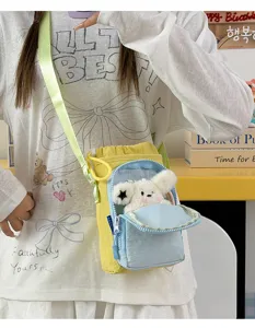 Close-up of cute yellow and blue crossbody water bottle bag with plush toy pendant detail.