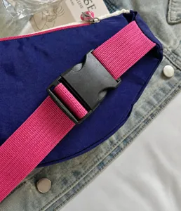Contrast color crossbody bag buckle detail, durable pink strap and sturdy plastic clasp.