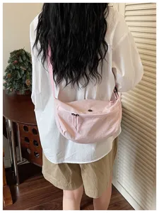 Pink nylon crescent crossbody bag detail view, casual lightweight dumpling shoulder bag style.