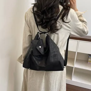 Vista dettagliata di un versatile zaino hobo in pelle nera con piccola tasca coordinata.