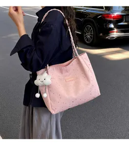 Dettaglio esterno della borsa tote rosa stellata con tracolla intrecciata e ciondolo.