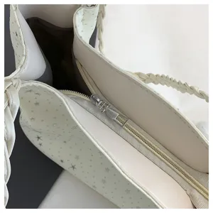 Dettaglio della borsa a tracolla bianca con motivo a stelle, elegante tracolla intrecciata e zip.