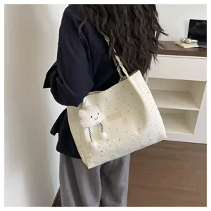 Vista dettagliata della borsa tote crema con stelle e ciondolo a nuvola per uso quotidiano.