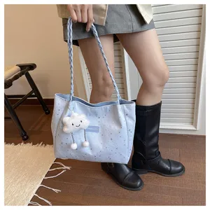 Vista di dettaglio della borsa tote azzurra con stampa a stelle, tracolla intrecciata e nuvola.
