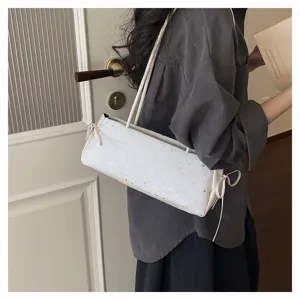 Close-up detail view of a stylish white star-patterned baguette shoulder bag worn by a model.