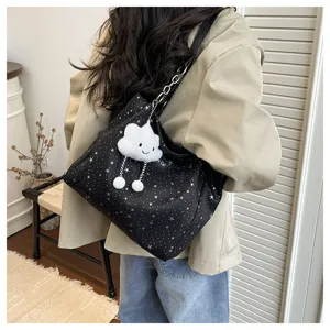Detail view of a stylish black star printed shoulder bag with fluffy cloud pendant and chain.