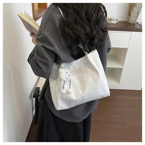 Detail shot of the white canvas shoulder bag featuring star patterns and a cute cloud plush pendant.