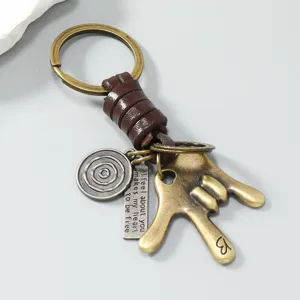 Gedetailleerd overzicht van vintage metalen sleutelhanger met leren koord en hanger.