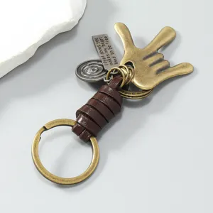 Gedetailleerd uitzicht van vintage metalen handgebaar sleutelhanger met gevlochten leer.