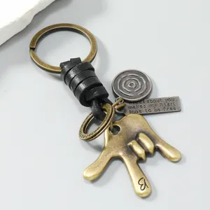 Close-up detail van vintage metalen gebaar sleutelhanger met leren koord en gegraveerd label.