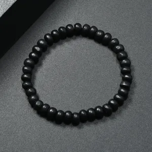 Vista detallada de la pulsera de cuentas de madera negra, textura lisa, elástico, estilo minimalista.