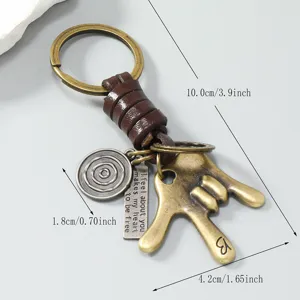 Vintage metalen gebaar sleutelhanger met gevlochten touw en unieke gegraveerde bedels.