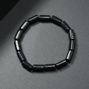Primer plano de pulsera de cuentas de madera cilíndricas negras, detalle de joyería vintage.