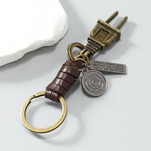Detailed shot of vintage metal plug keychain with braided leather strap and engraved metal tag.