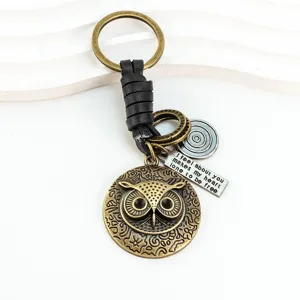 Porte-cles hibou en bronze vintage avec laniere en cuir noir et etiquette gravee.