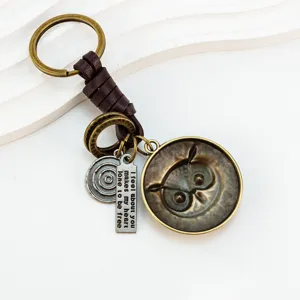 Détail de porte-clés hibou en bronze vintage avec pendentif gravé et lanière en cuir.