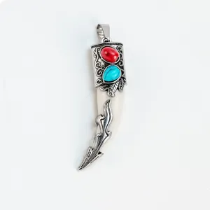 Detalle del colgante diente de lobo vintage, tapa de metal tallada con piedras turquesas.
