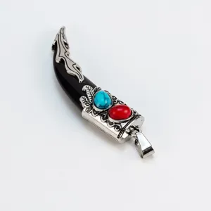 Detalle del colgante de cuerno vintage con incrustación de turquesa y piedra roja en resina.