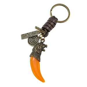 Llavero vintage de diente de lobo con cuerda de cuero trenzado, dije de cabeza de león y placa.