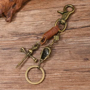 Close-up detail of retro punk metal skull keychain with leather wrap and dice charm.