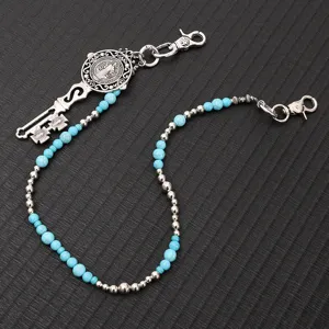Detail shot of punk style turquoise bead pants chain and metal key pendant accessory.