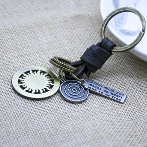 Close-up detail of creative Nordic leather keychain with metal sun wheel pendant and engraved tag.