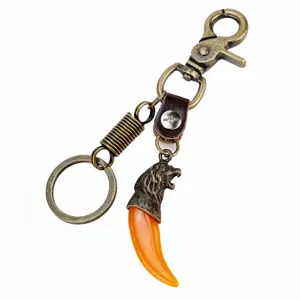 Detalle de llavero de cabeza de león de bronce, colgante de diente naranja con cierre.