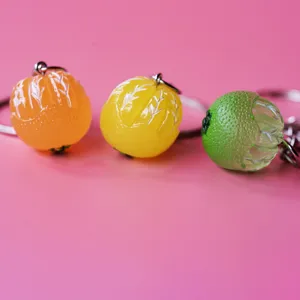 Detailed close-up view of creative fruit keychains featuring orange and lime designs on pink.