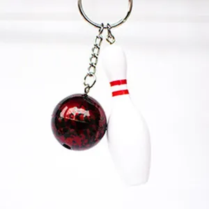 Close-up view of a miniature bowling pin and ball keychain with detailed red accent lines.