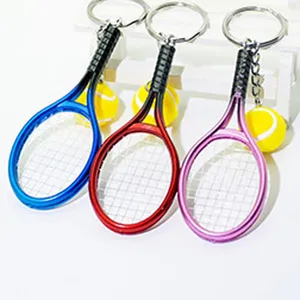 Close-up detail view of colorful mini tennis racket and tennis ball keychain set, metallic finish.
