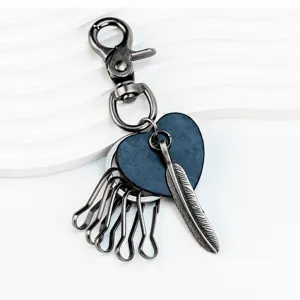 Vintage feather keychain detail shot, antique bronze metal craft, dark blue heart leather pendant.