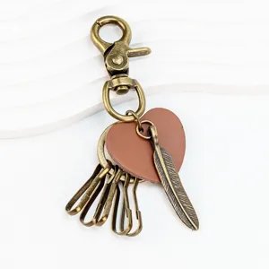Detail shot of vintage bronze feather heart keyring pendant, delicate hardware craft.