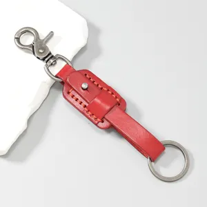 Dettaglio in primo piano del portachiavi in pelle rossa con gancio e anello in metallo.