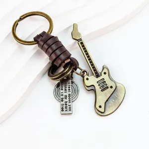 Vintage metalen gitaar sleutelhanger met leren riem wikkel en gegraveerd metalen label detail.