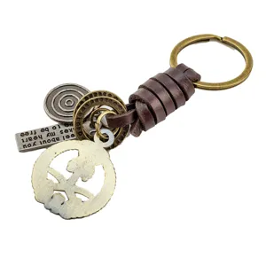 Vintage woven leather keychain with metal charms and unique emblem pendant for keys.