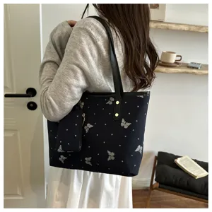 Detailed lifestyle view of black canvas tote bag with silver butterflies and cute pouch.